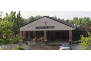 A view of a church building with a cross and a parking lot in front.