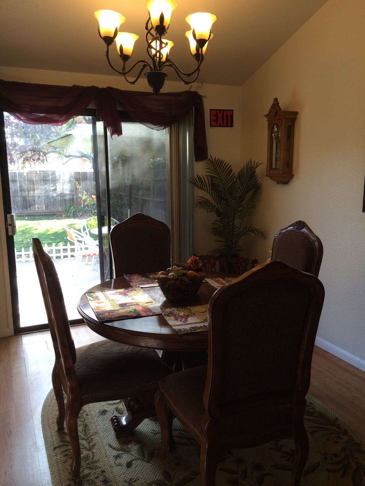 A cozy dining room with a round table and chairs, featuring a large sliding glass door leading to the garden.