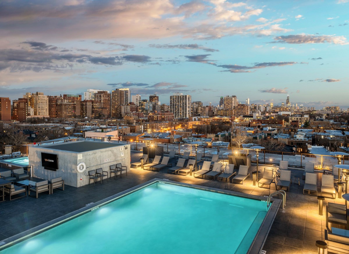 A serene rooftop pool overlooking the city skyline at sunset.