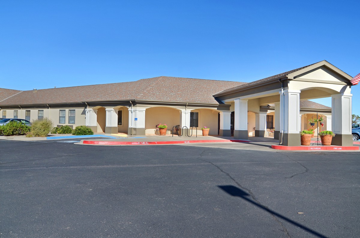 An exterior view of a building with a parking lot under a clear blue sky.
