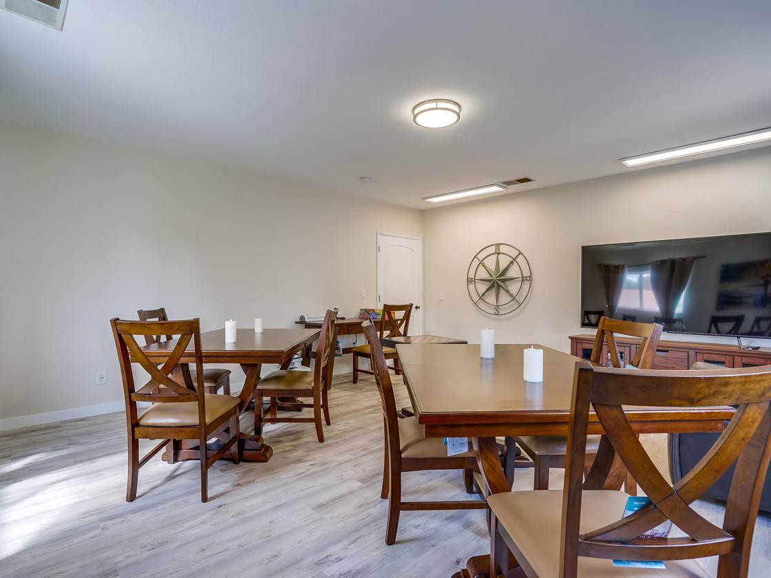 A modern dining room with wooden tables and chairs, featuring a television and contemporary decor.