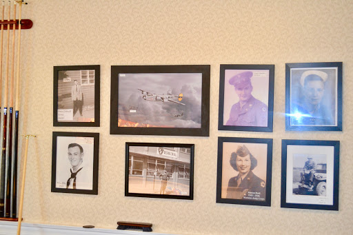 A collection of vintage photographs displayed in black frames on a wall, showcasing a variety of historical figures and scenes.