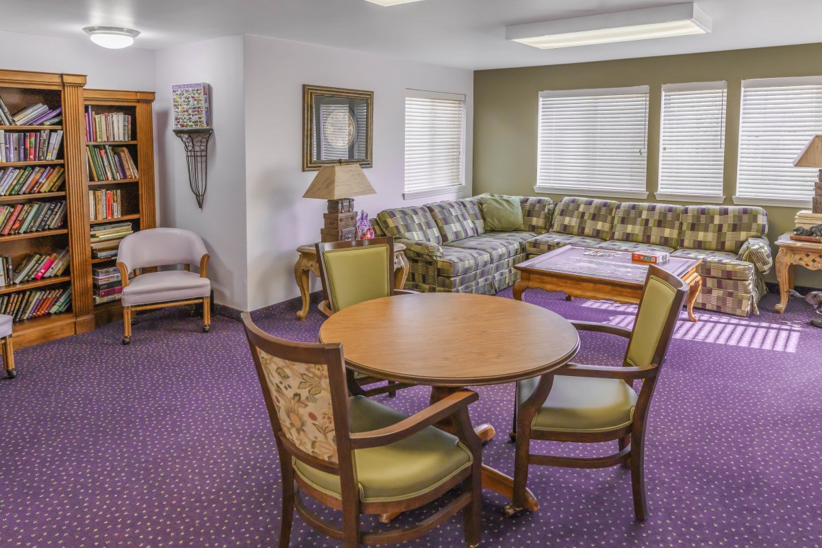 A cozy living room with a round table and chairs, a floral-patterned sofa, and decorative elements.