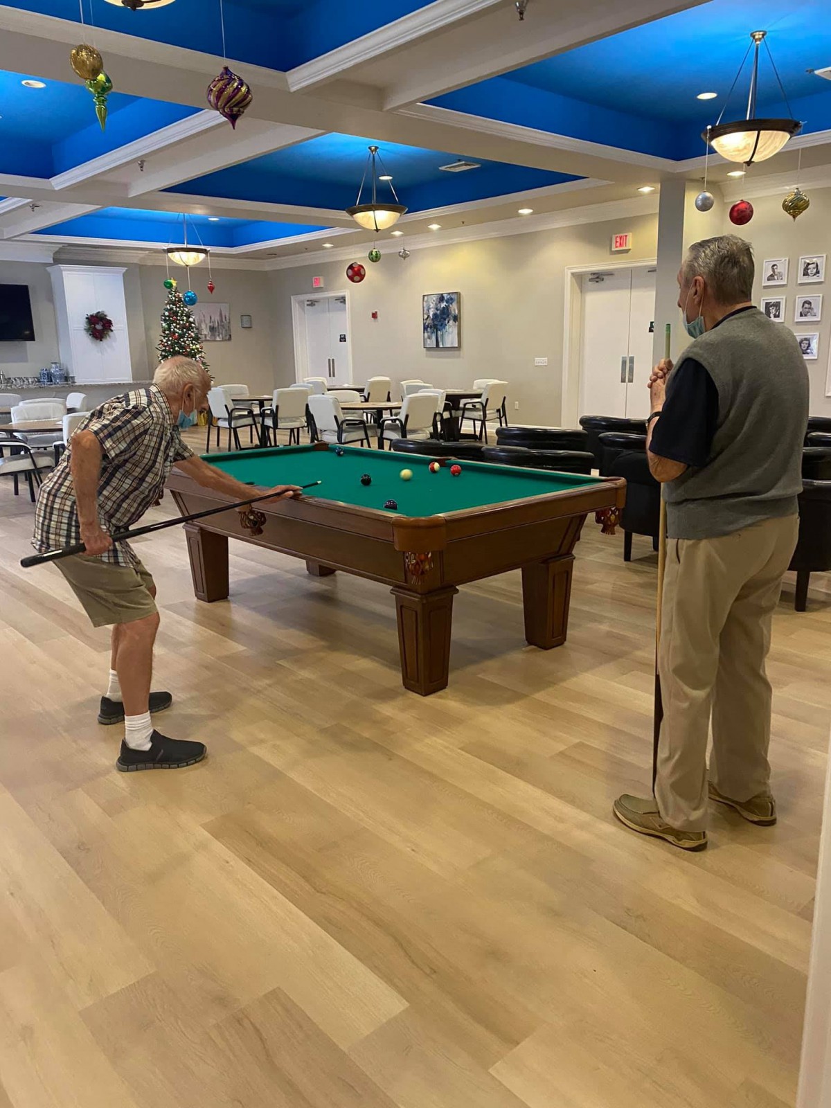 Two people playing billiards in a recreational room.