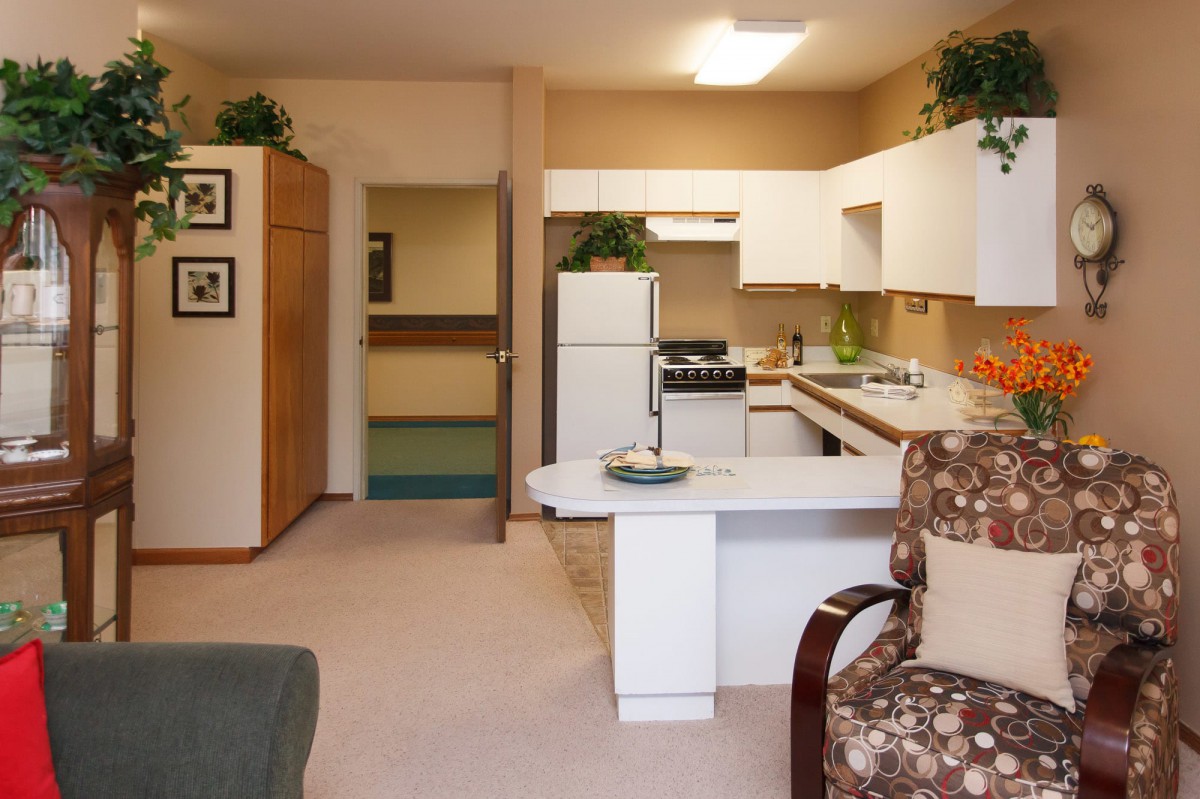 A modern apartment kitchen with white cabinets and an open layout.