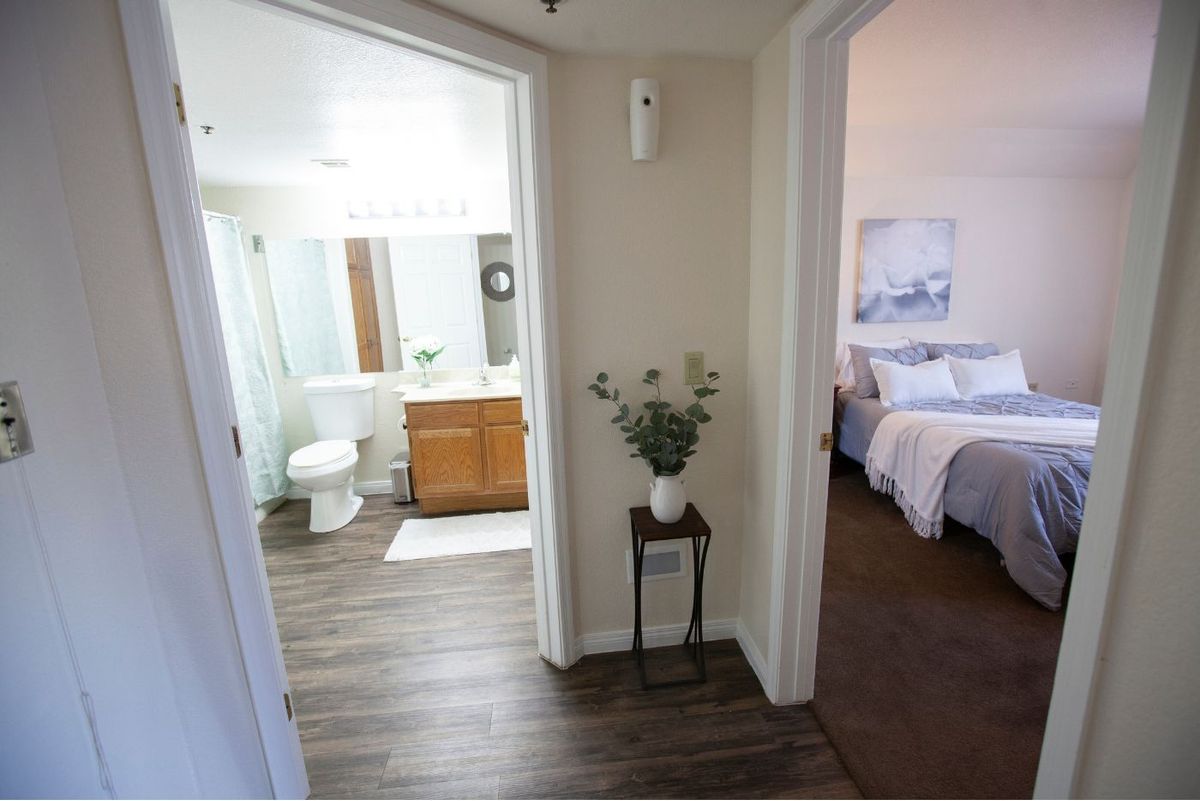 A modern home interior featuring a hallway with a view into a bathroom and bedroom.