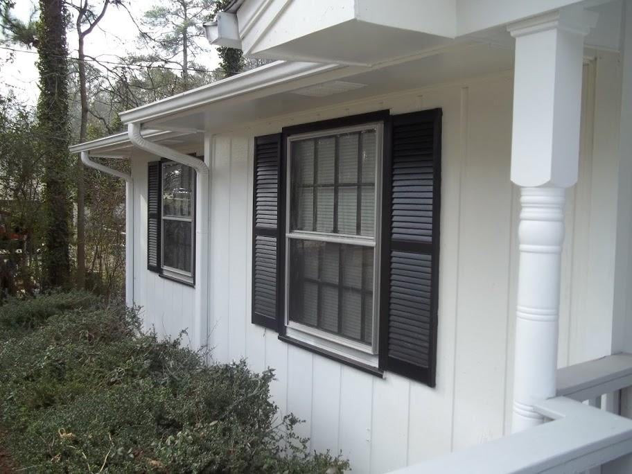 A residential house with white siding and black shuttered windows.