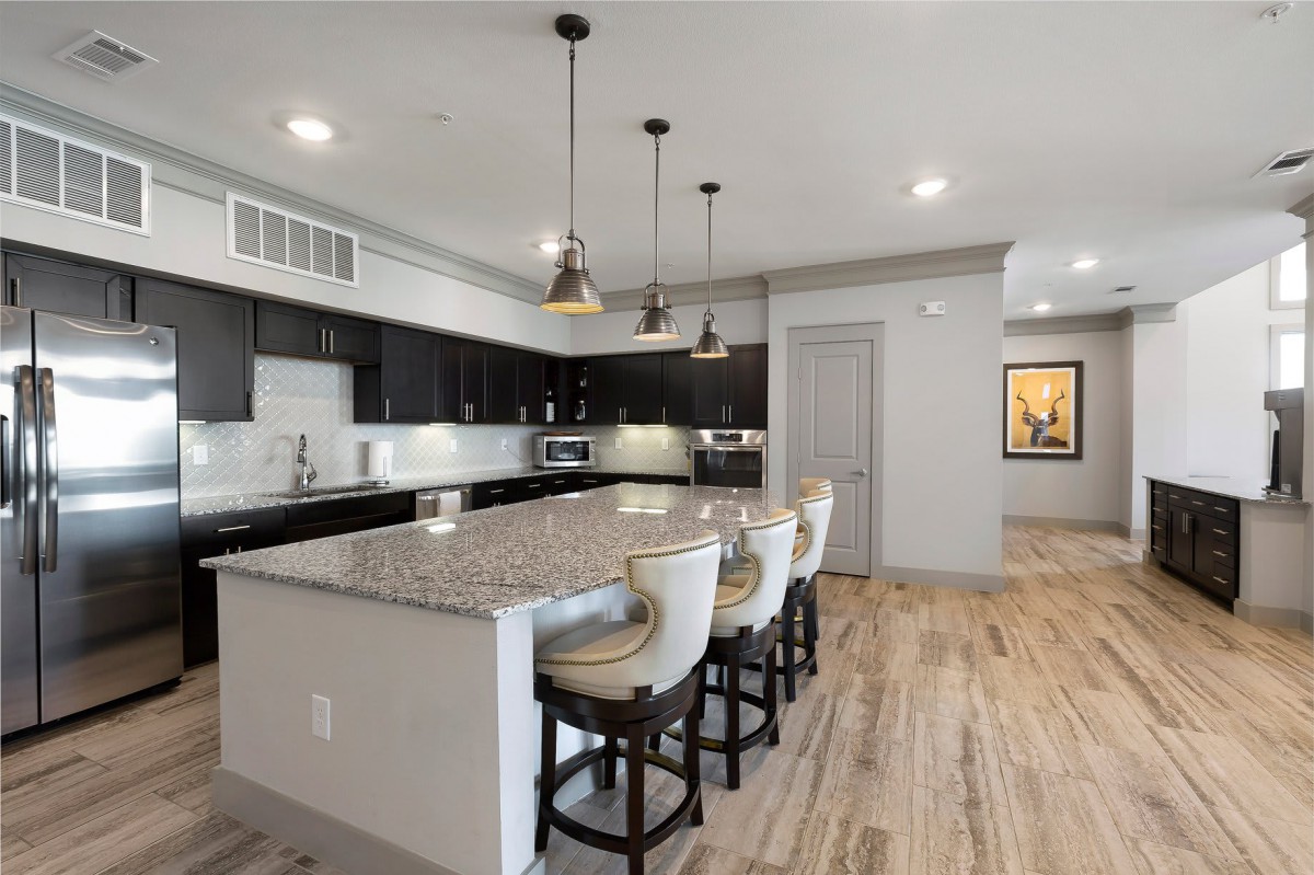A modern kitchen with a large island, bar stools, and pendant lighting.