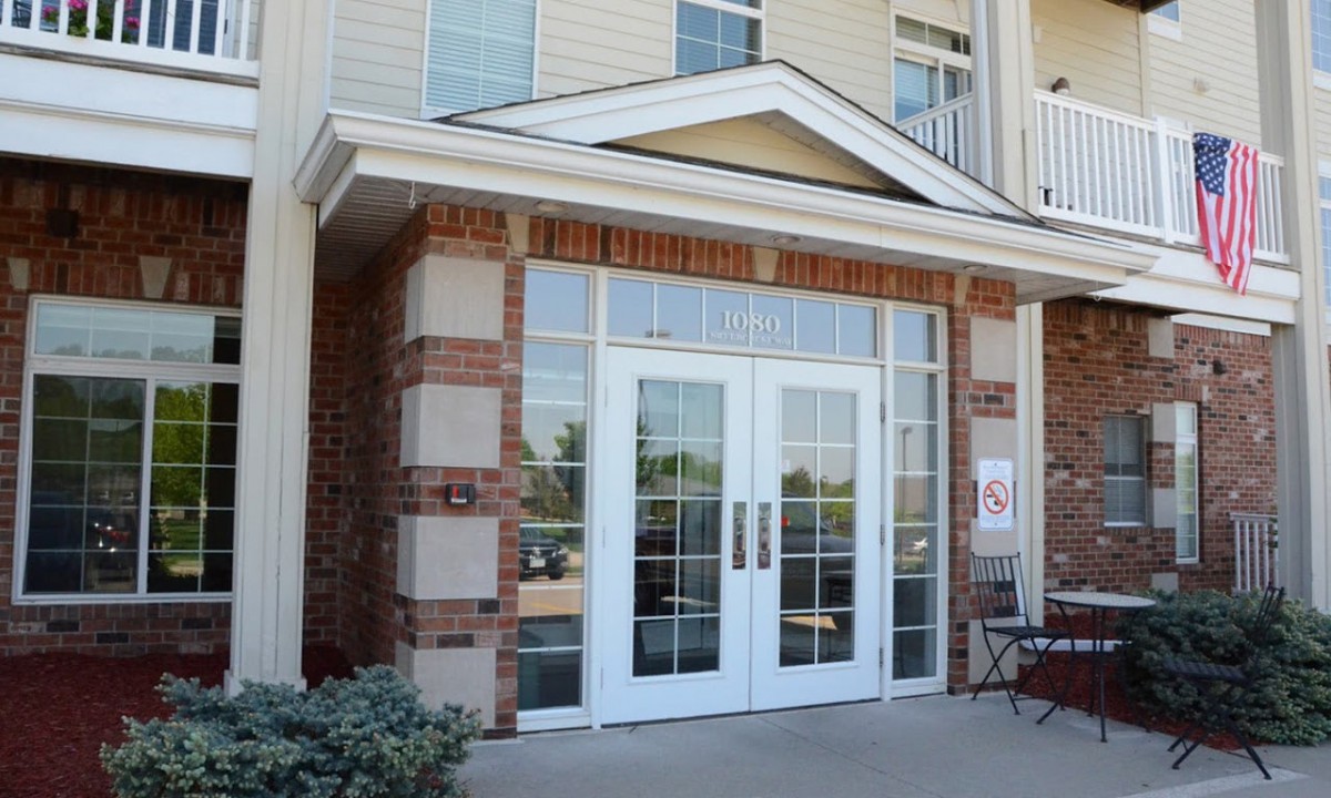 Front entrance of a building with glass double doors and brick accents.