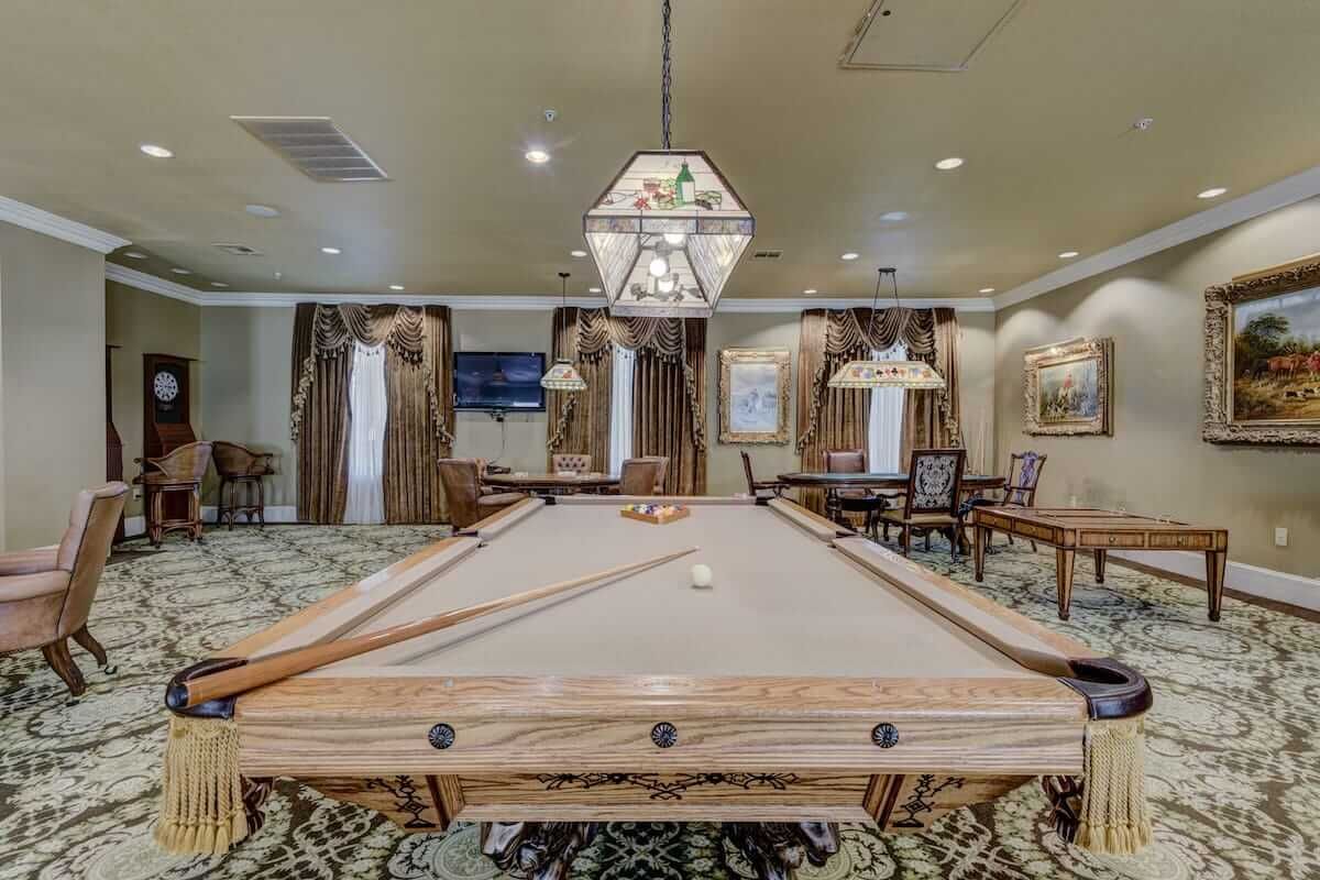 A luxurious billiards room with a pool table and elegant lighting fixtures.