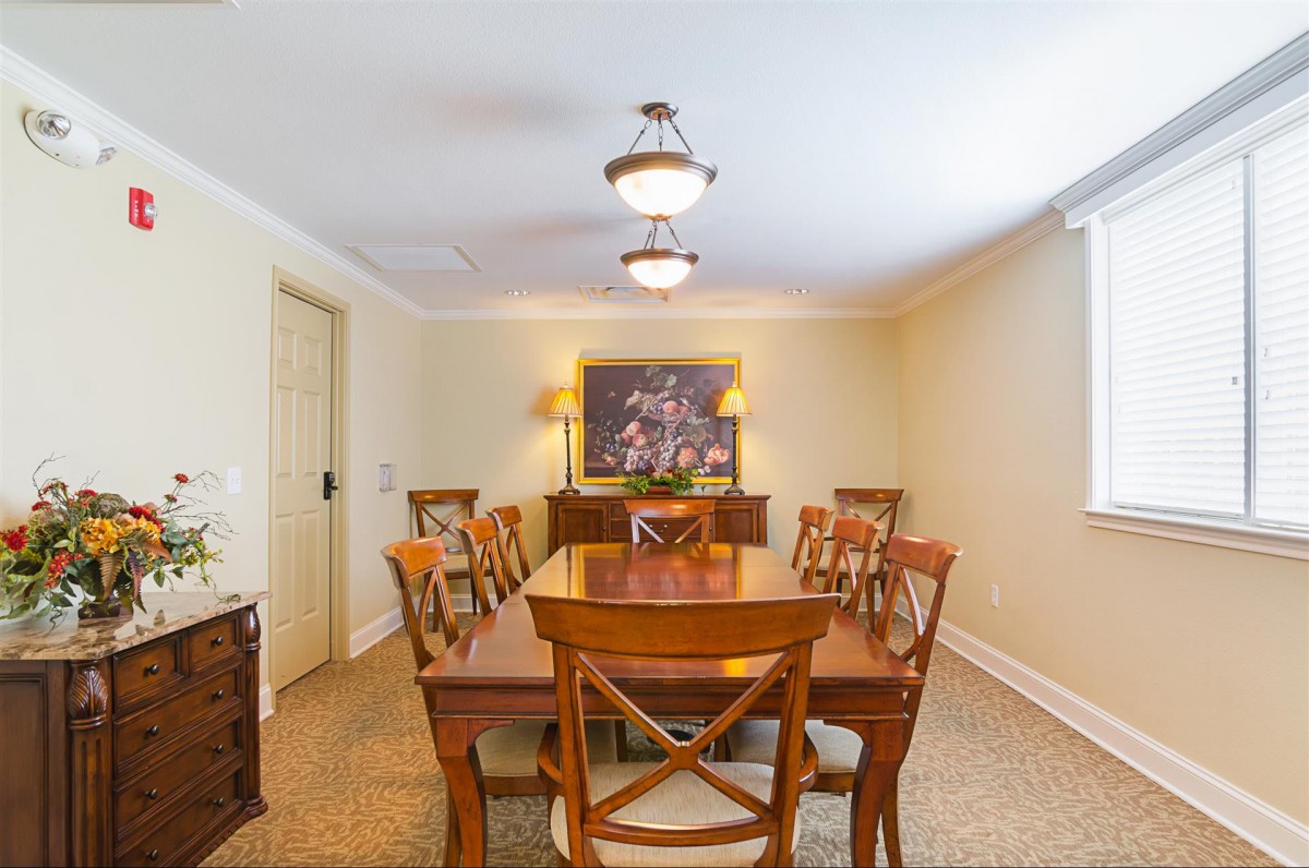 A neatly arranged dining room with a wooden table, chairs, and a chandelier overhead.