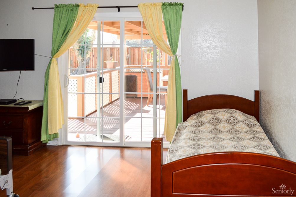 A bedroom with a single bed and sliding glass doors leading to an outdoor space.