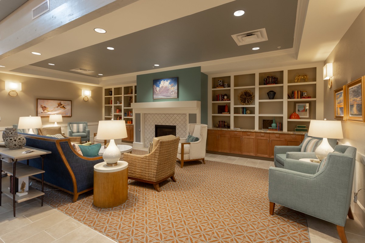 A cozy living room with modern furnishings, featuring a fireplace and built-in bookshelves.