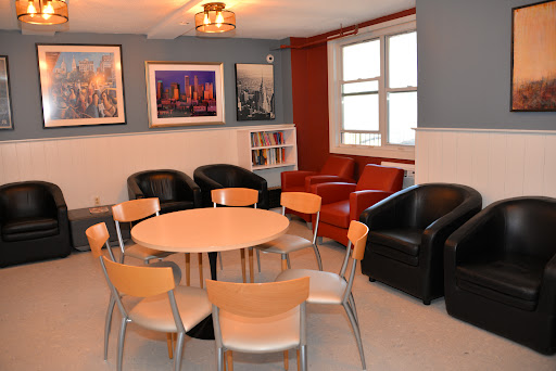 A cozy lounge area featuring a circular table surrounded by chairs and leather seating, complemented by framed artwork on the walls.