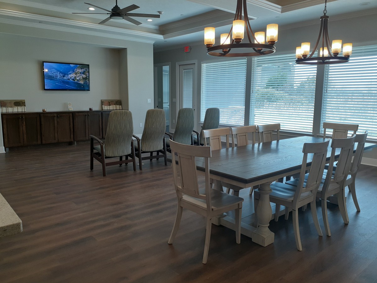 A spacious dining room with a large table and chairs, featuring hardwood floors and modern lighting.