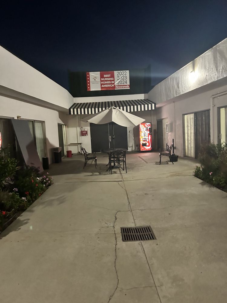 A nighttime view of a courtyard with a tent, tables, and chairs between two buildings.