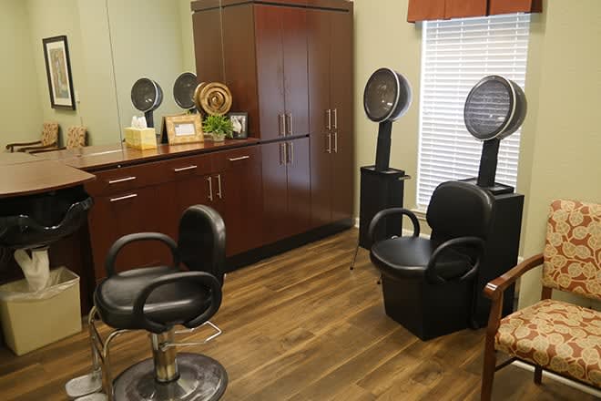 A cozy salon interior with hair styling chairs and standing hair dryers.
