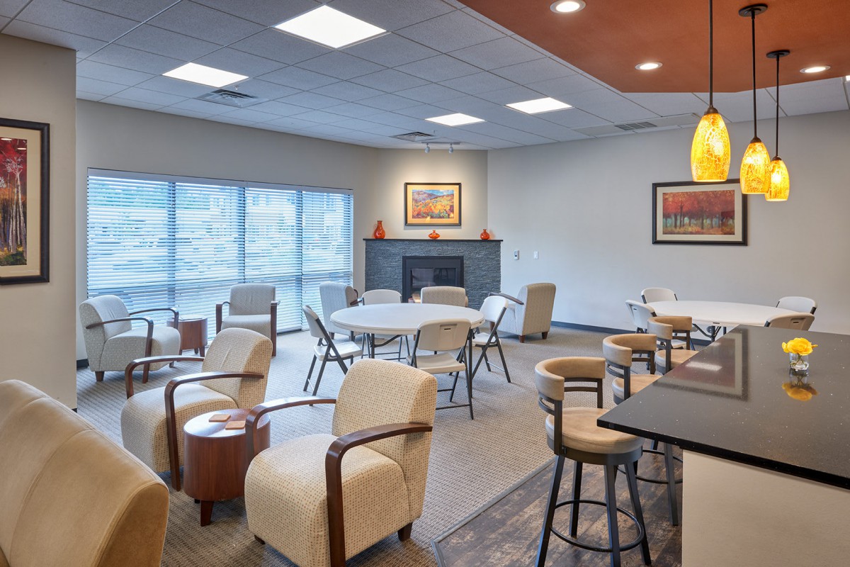A cozy lounge area with comfortable seating, tables, and artwork on the walls.