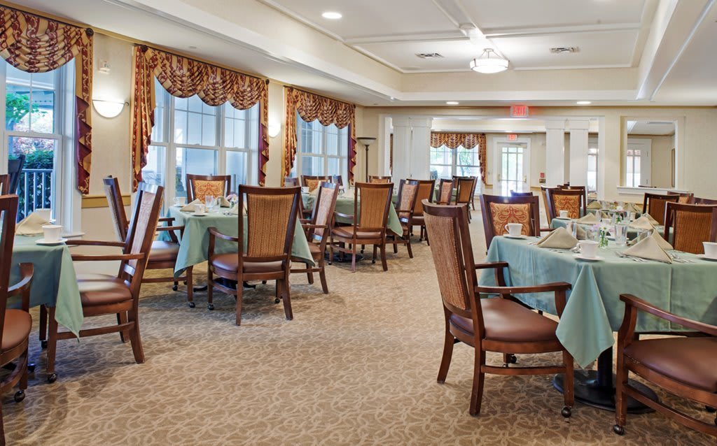 An elegantly arranged dining room with neatly set tables and upholstered chairs.