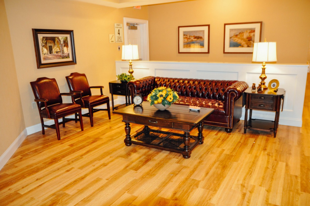 A cozy living room with a classic leather sofa, two chairs, and a wooden coffee table on a polished hardwood floor.