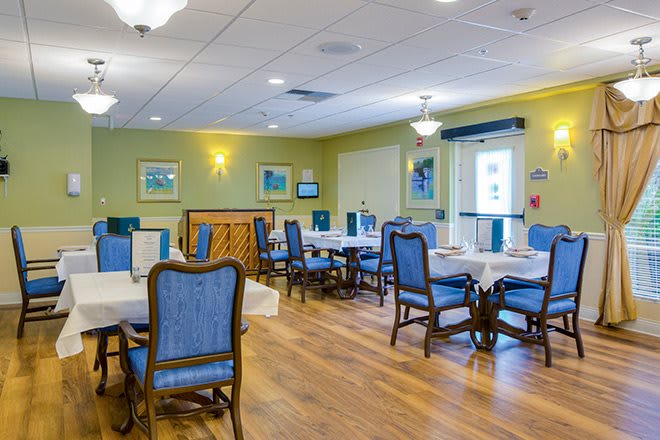 A well-lit dining room with blue upholstered chairs and wooden tables.