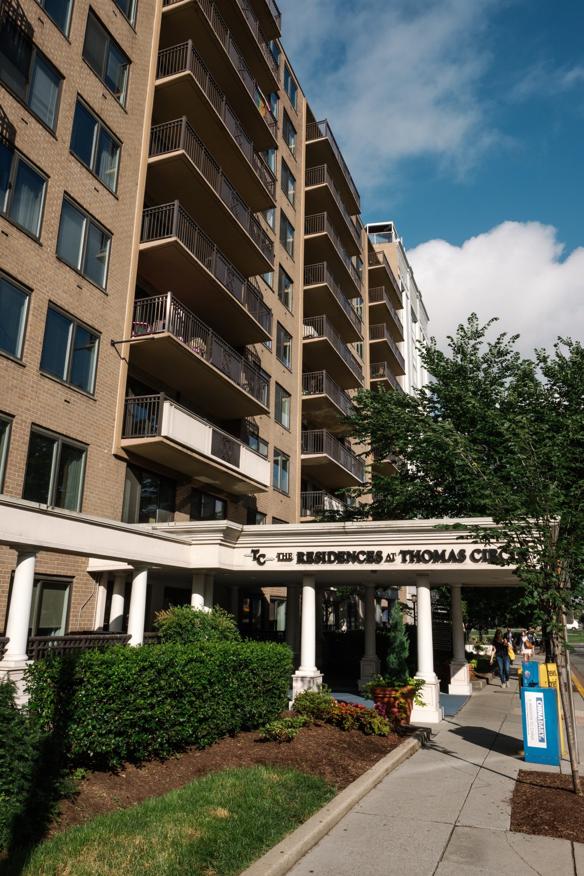 A residential apartment building with balconies and a sign reading 'The Residences at Thomas Circle'.