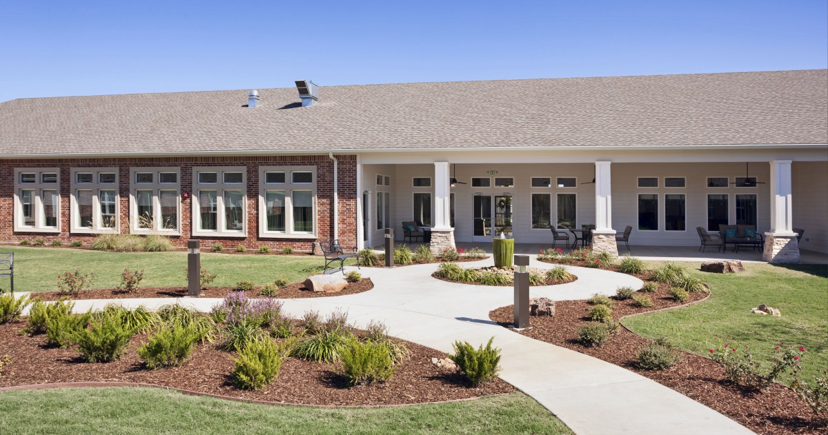 A modern building with a landscaped front yard and a winding pathway.