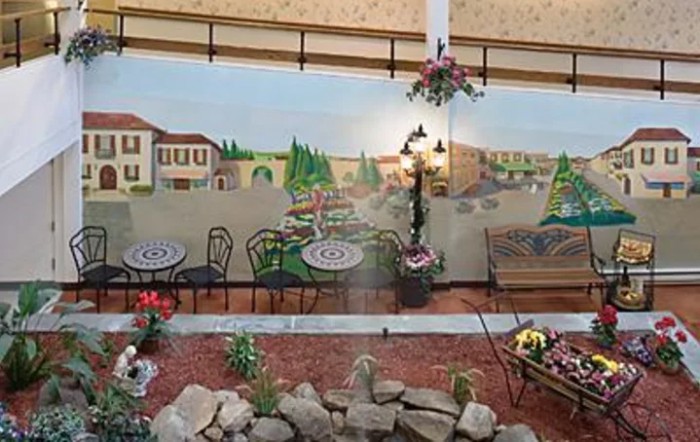 A mural depicting a quaint outdoor cafe with tables, chairs, and garden decor.