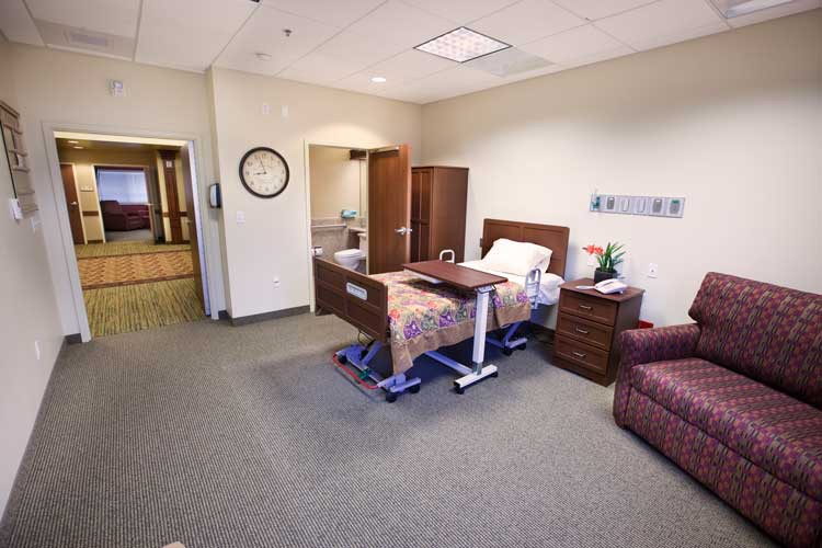 A clean and organized hospital room with a bed, side table, and armchair.