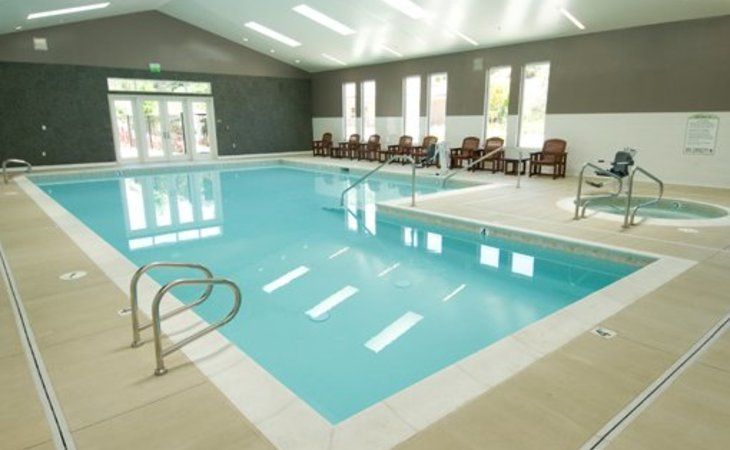 A serene indoor swimming pool area with lounge chairs.
