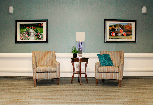 A cozy seating area featuring two striped chairs, a small table with a plant, and framed artwork on the walls.
