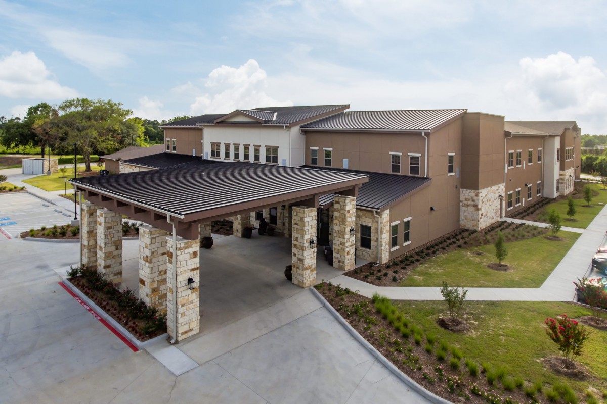 A modern building with a covered entrance and landscaped surroundings.