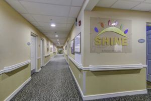 A well-lit hallway with carpet flooring, decorated walls, and visible signage.