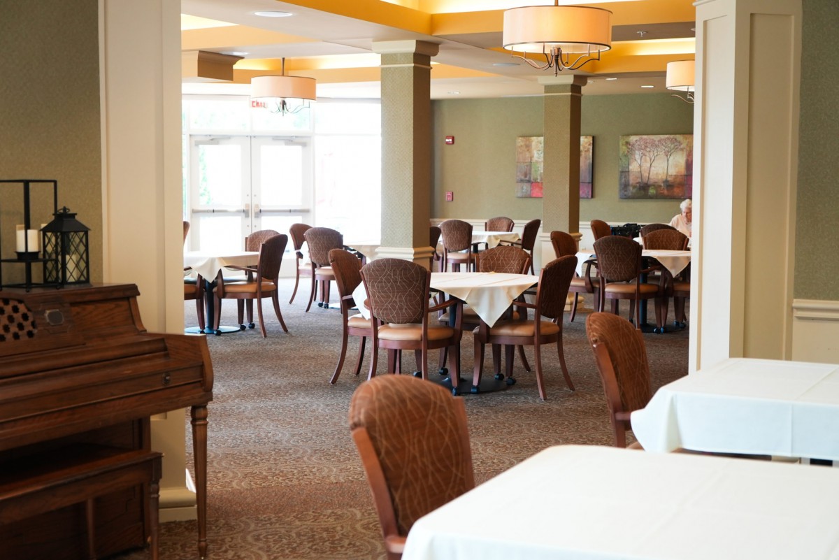 An empty restaurant dining area with neatly arranged tables and chairs, illuminated by warm lighting.
