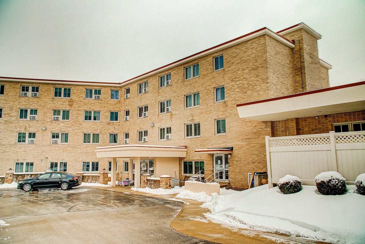 A multi-story brick apartment building with a snow-covered parking lot.