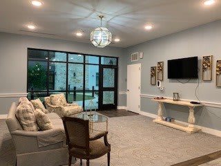 A modern living room with comfortable seating and a large TV, illuminated by a stylish chandelier.