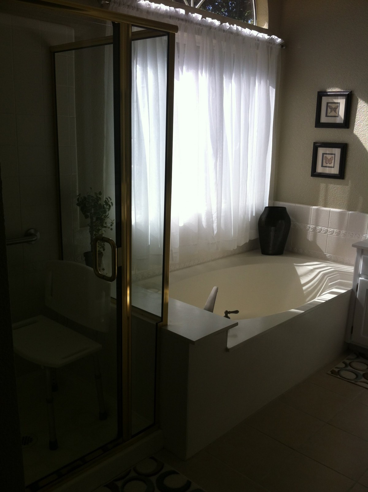 A well-lit bathroom with a large bathtub and a glass shower enclosure.