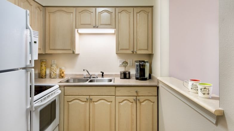 A compact kitchen with wooden cabinets, a double sink, and a coffee maker on the countertop.