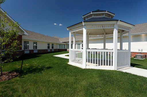 A beautifully designed gazebo surrounded by lush green grass under a clear blue sky.