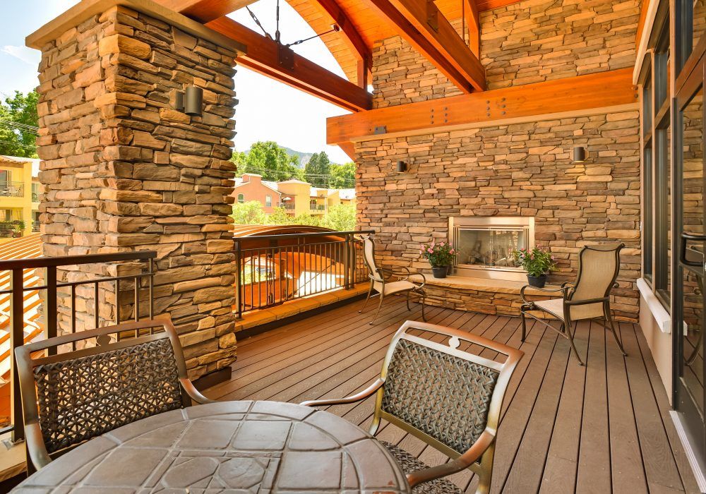 A cozy outdoor patio with a stone fireplace and comfortable seating.