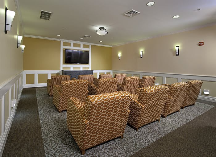 A small home theater room with multiple armchairs facing a large television screen.