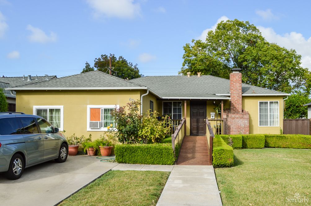 A charming single-story house with a driveway and neatly trimmed hedges.