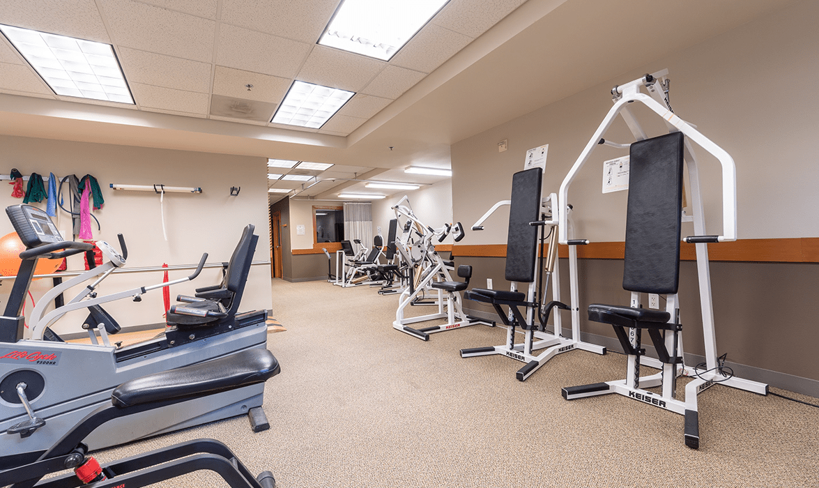A modern gym with various exercise equipment and workout machines.
