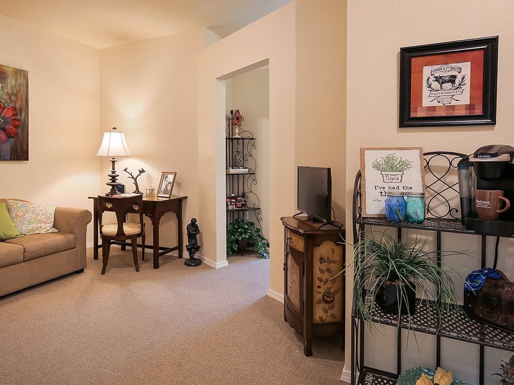 A cozy living room with a small desk, decorative items, and warm lighting.
