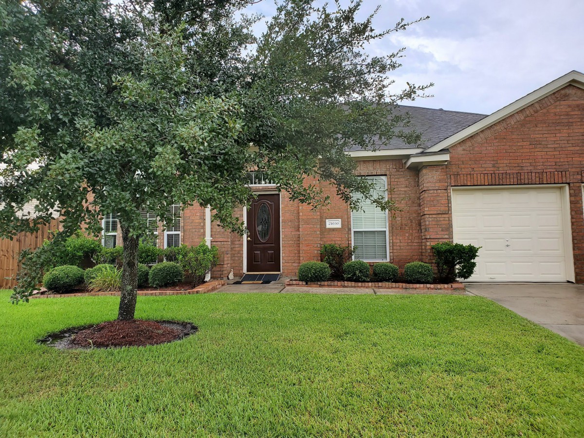 A brick house with a well-maintained lawn and front yard tree.