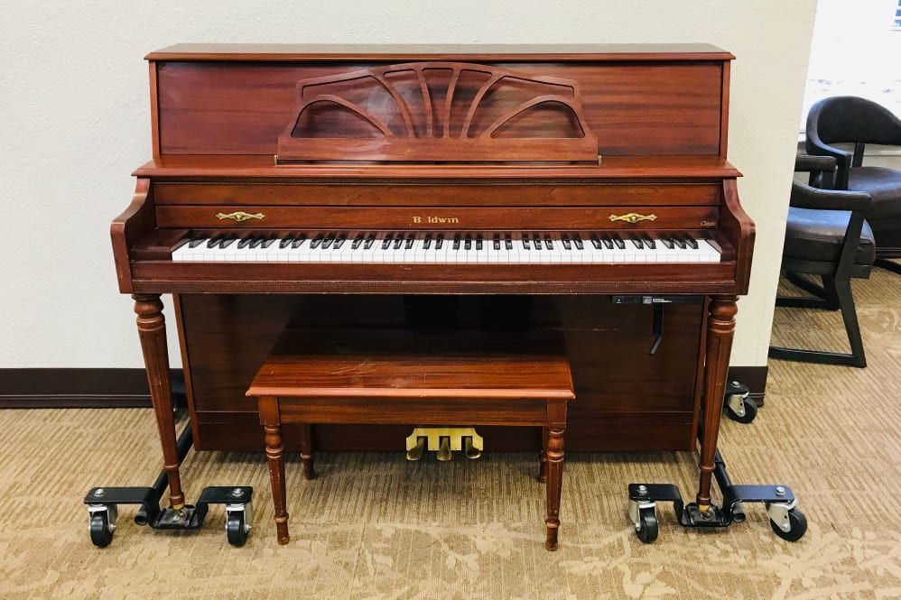 A classic wooden upright piano with a matching bench.