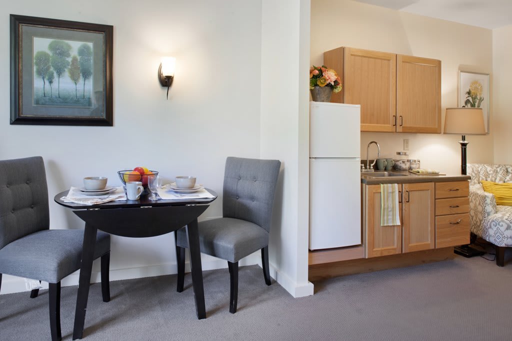 A cozy kitchen and dining area with a small table, chairs, and essential appliances.