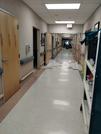 A view of a hospital hallway lined with doors and medical equipment.