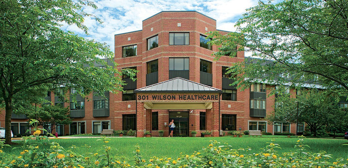 A brick healthcare facility with a well-maintained green lawn.