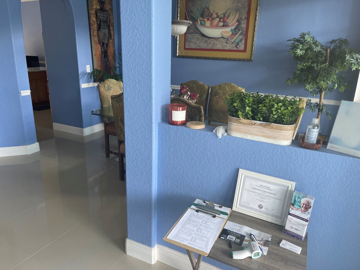 A cozy interior space featuring a blue wall, decorative plants, and framed certificates on a table.